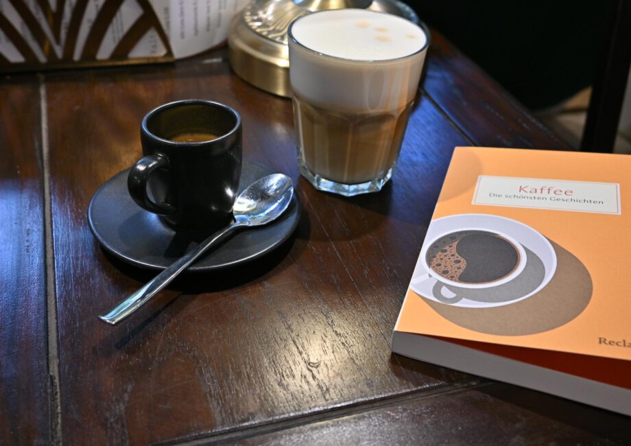 Ein Foto einer Tasse Espresso neben dem Buch "Kaffee" aus dem Reclam Verlag auf einem Café-Tisch